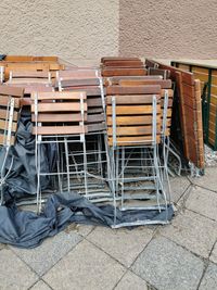 High angle view of chairs on footpath against wall