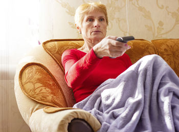 Young woman using phone while lying on bed at home