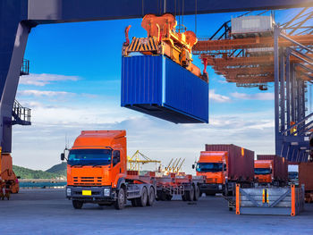 Industrial port crane lift up loading export containers box onboard from truck at port of thailand.