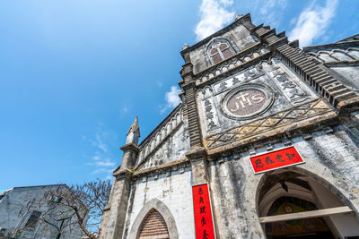 Low angle view of clock tower amidst buildings against sky