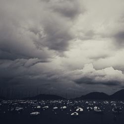 Boats in harbor against cloudy sky