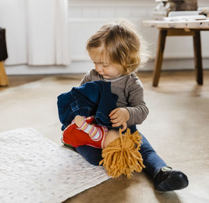 Girl playing with doll while sitting at home