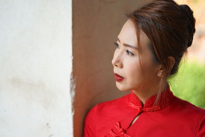 Close-up of thoughtful woman in traditional clothing standing by wall