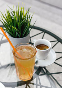 Close-up still life image of a glass of ice tea and cup of espresso coffee on table in cafe