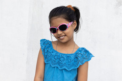An indian girl wearing sunglasses looking at camera with smiling face in summer on white background