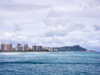 Sea by city buildings against sky