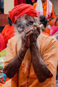 Close-up portrait of man in traditional clothing smoking pipe