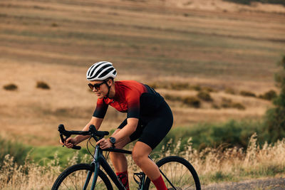 Woman riding bicycle near field