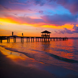 Pier over sea against sky during sunset