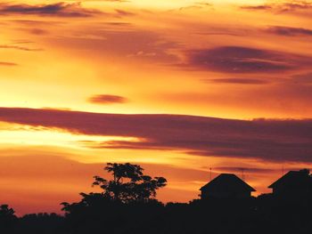Silhouette trees against dramatic sky during sunset