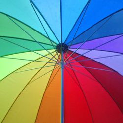 Low angle view of multi colored umbrella against blue sky