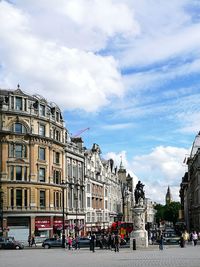 Statue in city against cloudy sky