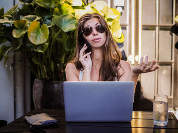 Young woman using phone while sitting on table