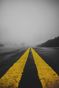 Surface level of yellow road against sky