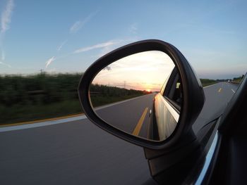 Reflection of car on side-view mirror during sunset