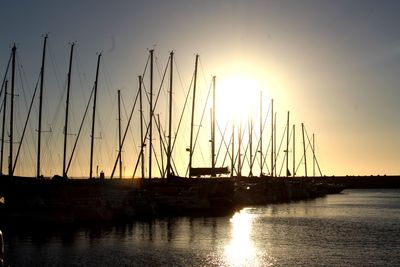 Sailboats moored on sea against sky during sunset