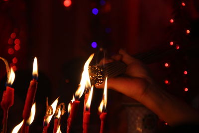 Cropped hand burning incense sticks at temple