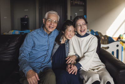 Portrait of adult daughter and her senior parents laughing