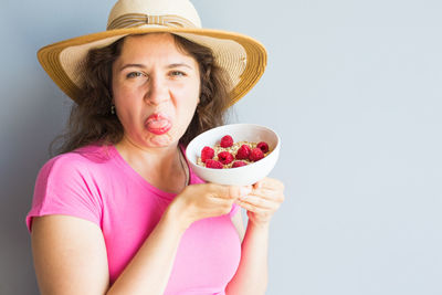 Portrait of a woman holding apple against white background