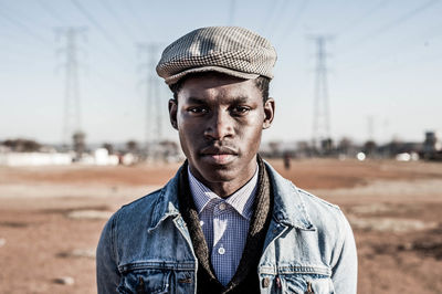 Portrait of young african man wearing cap while standing against sky