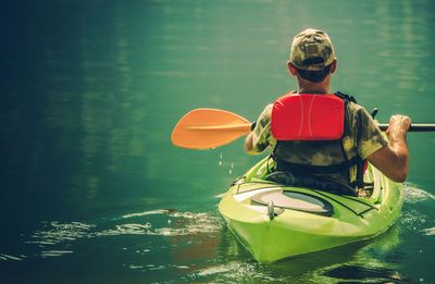 Rear view of man on boat in river