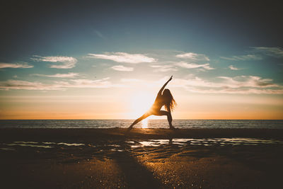 Silhouette woman on beach against sky during sunset