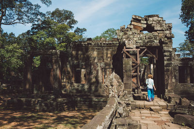 Rear view of mid adult woman walking at ankor wat temple