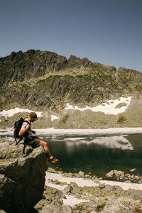 Side view of man looking at lake against mountain