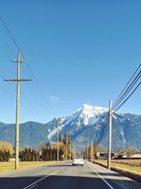 Road by mountain against clear blue sky