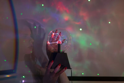 Midsection of woman holding illuminated lights at night