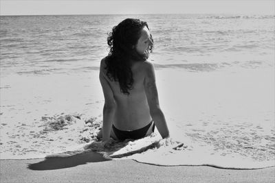 Rear view of shirtless boy on beach