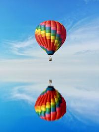 Hot air balloon flying over sea against blue sky