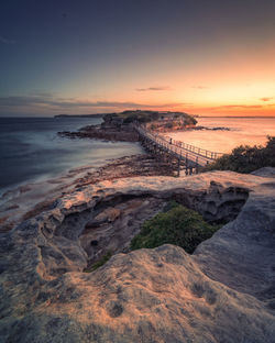 Scenic view of and island bay against sky at sunset