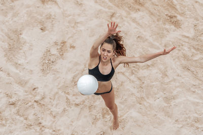 High angle view of woman playing volleyball on sand at beach