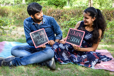 Indian couple posing for maternity baby shoot. the couple is posing in a lawn with green grass