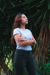 Young woman standing against plants