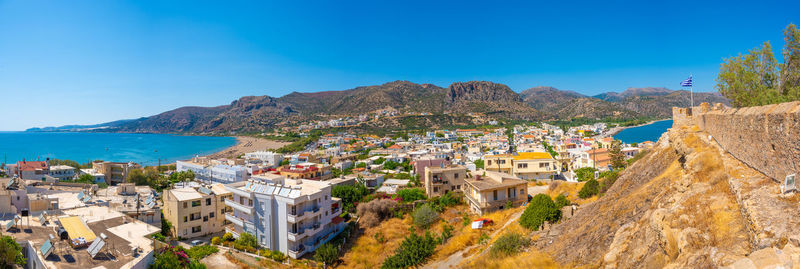 High angle view of townscape by mountains against clear blue sky