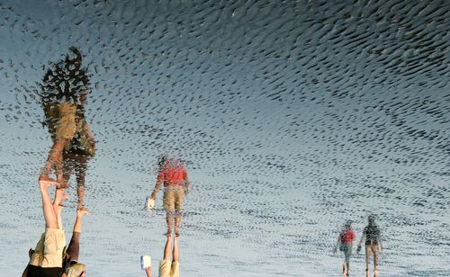 Reflection of people walking on shore