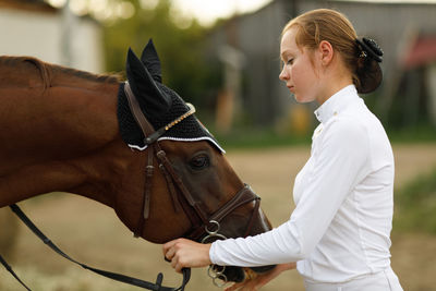 Side view of woman holding horse