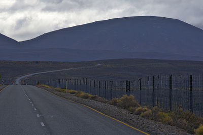 Road leading towards mountain against sky