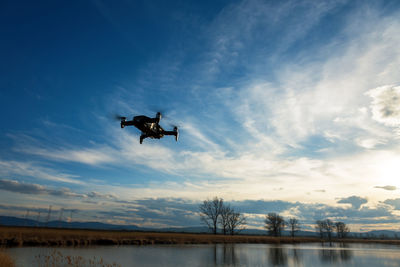 Small modern drone hovering taking picture of sunset.