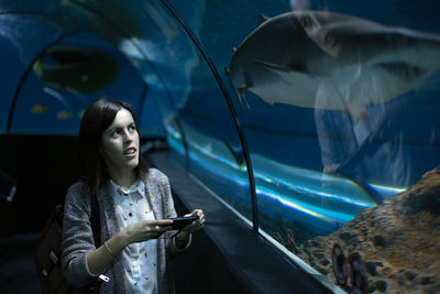 Young woman looking at fish in aquarium