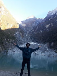 Full length of young man standing on mountain lake