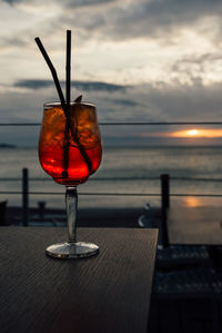 Wineglass on table against sea during sunset. cocktail glass on table against sea during sunset 