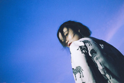 Low angle view of woman against clear blue sky