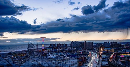 Coney island against sky during sunset in city