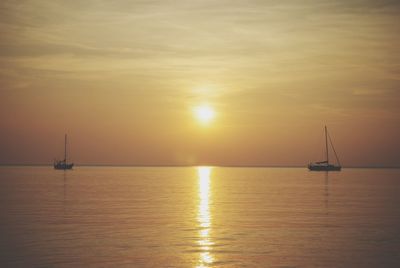 Boat sailing in sea at sunset