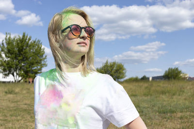 Portrait beautiful white blond woman with colored dye, powder on face and cloth on holi colors