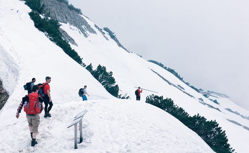 People walking on snowcapped mountain against sky