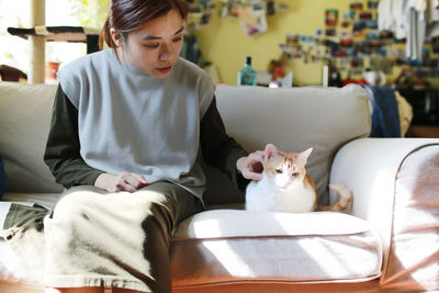 Woman with cat sitting on sofa